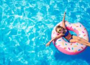 Funny Little Girl Playing On Inflatable Donut In Pool
